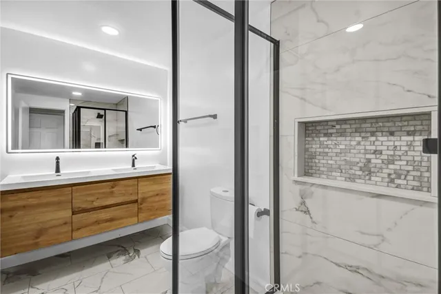 a bathroom with a granite countertop sink a toilet and shower