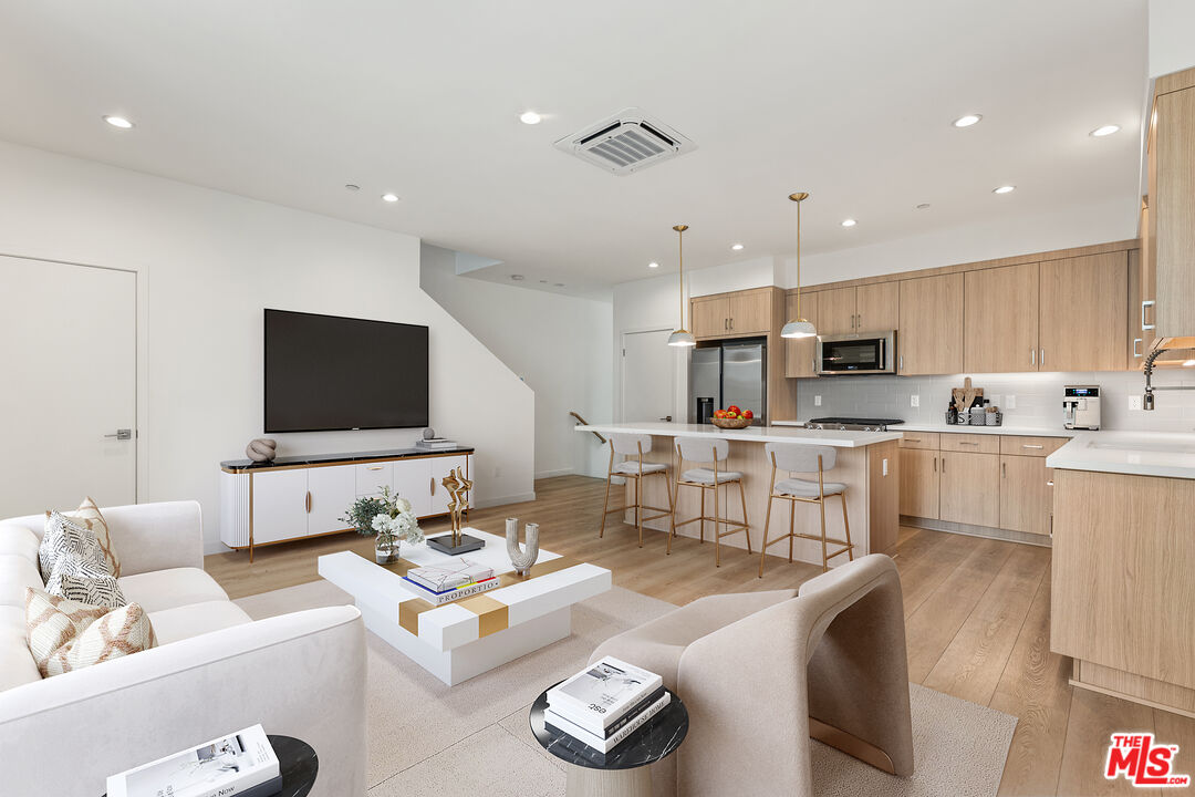 a living room with furniture kitchen and a flat screen tv