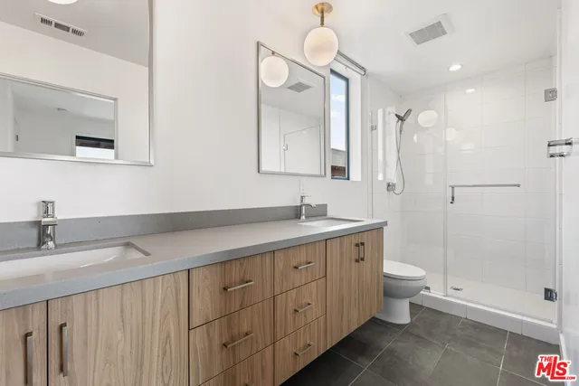 a spacious bathroom with a double vanity sink toilet mirror and shower