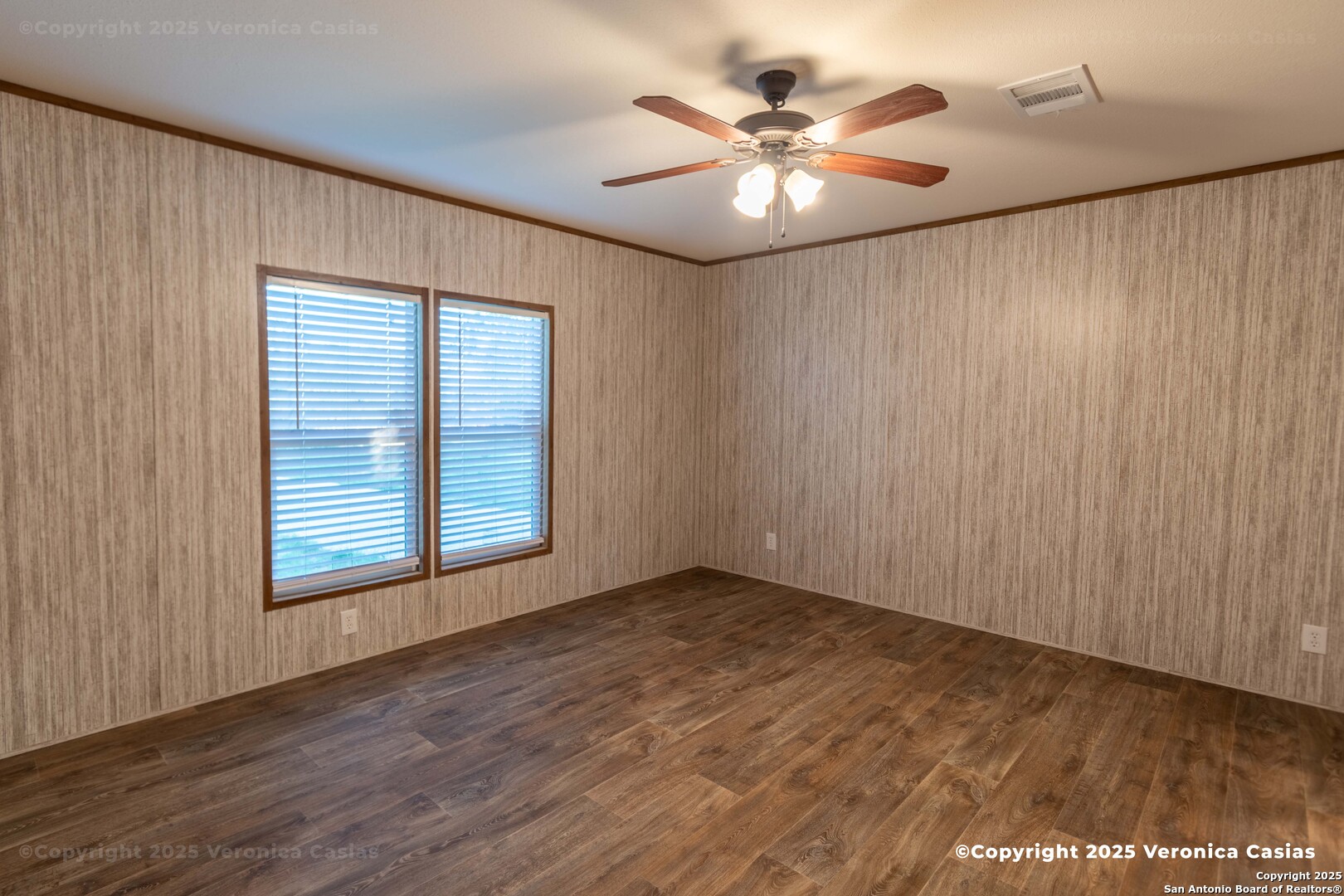 336 County Road 6846 Lytle, TX 78052 - Photo 14 of 20 an empty room with wooden floor chandelier fan and windows