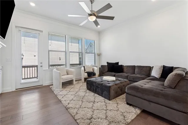 a living room with furniture a large window and wooden floor