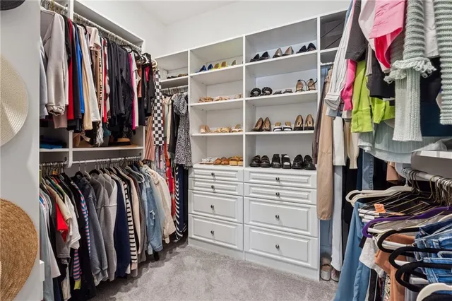 a view of walk in closet with clothes and shoes