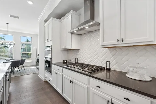 a kitchen with stainless steel appliances granite countertop a sink a stove and a wooden floors