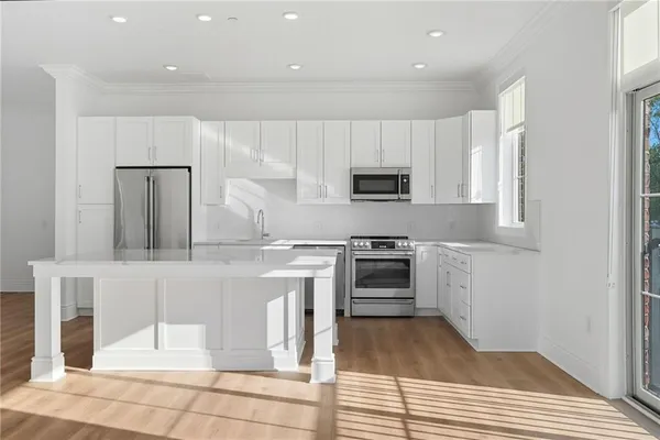 a kitchen with kitchen island granite countertop a stove top oven a sink dishwasher and a refrigerator with wooden floor