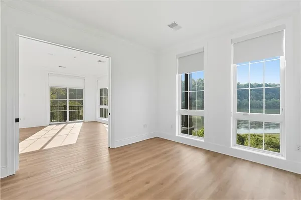 a view of an empty room with wooden floor and windows