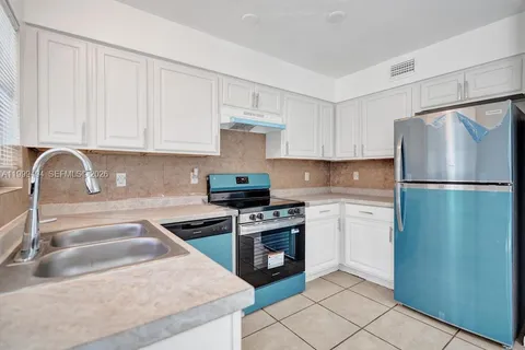 a kitchen with a refrigerator sink and cabinets