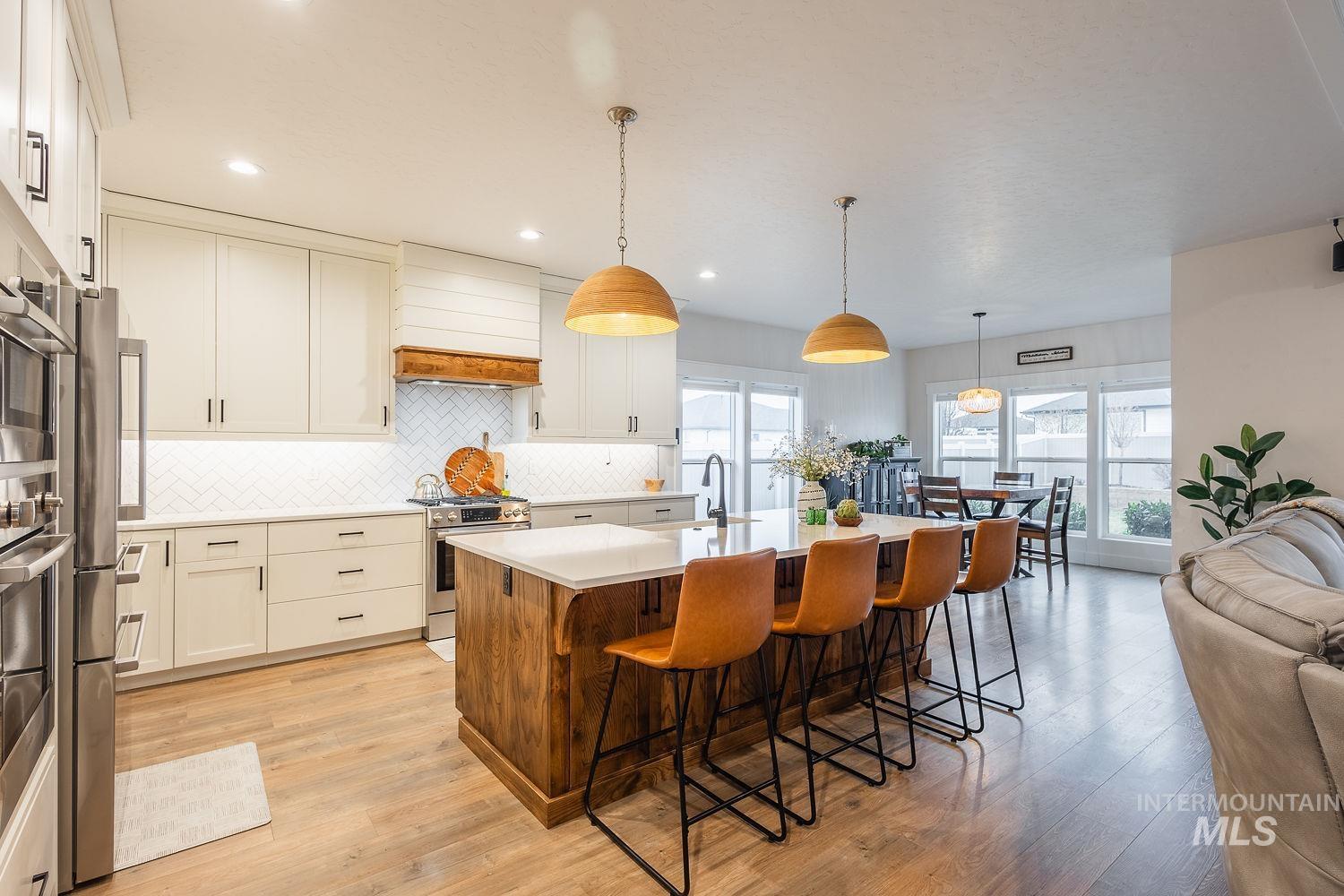 2206 Seafarer Court Middleton, ID 83644 - Photo 4 of 37 Kitchen with a center island with sink, decorative light fixtures, a kitchen breakfast bar, light wood-type flooring, and appliances with stainless steel finishes