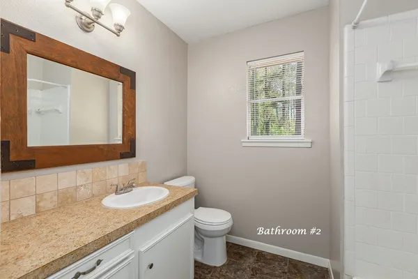 a bathroom with a granite countertop sink toilet and shower