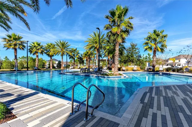 a view of a swimming pool with a lounge chair and palm trees