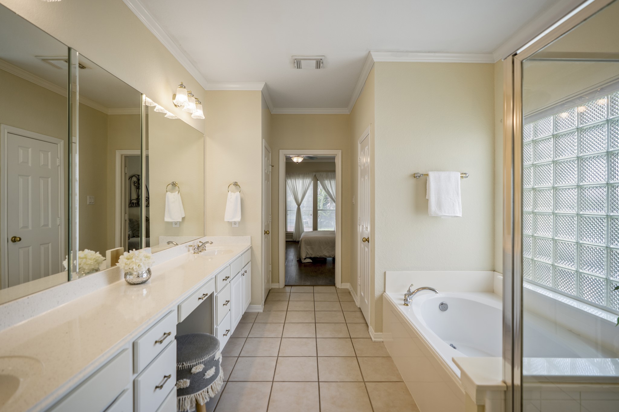 5807 Sequoia Trace Court Spring, TX 77379 - Photo 18 of 50 This wider view of the primary bath shows the extended dual-sink vanity, soaking tub, separate shower, and a direct connection back to the bedroom, with the glass block window adding natural light and privacy.