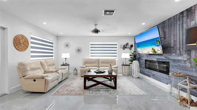 a living room with furniture a flat screen tv and kitchen view
