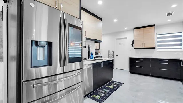 a kitchen with stainless steel appliances kitchen island granite countertop a table chairs and a refrigerator