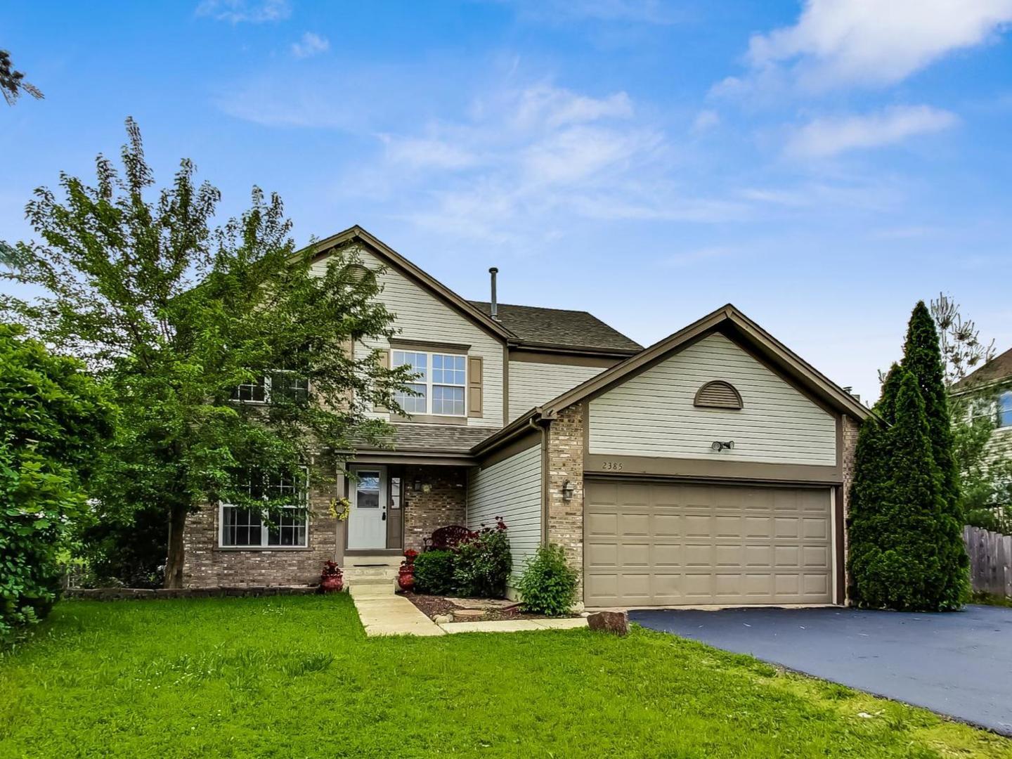 2385 North Periwinkle Way Round Lake Beach, IL 60073 - Photo 2 of 51 a front view of a house with a garden and trees