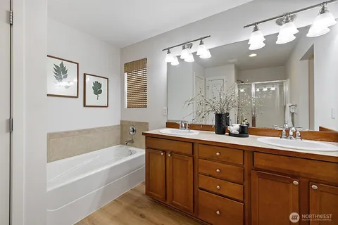a bathroom with a tub a sink double vanity and a mirror