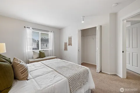 a bedroom with a large bed and two windows