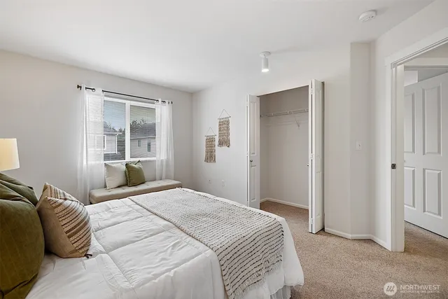 a bedroom with a large bed and two windows