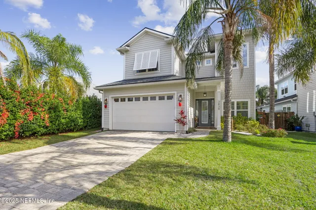 a view of a house with a yard and palm trees