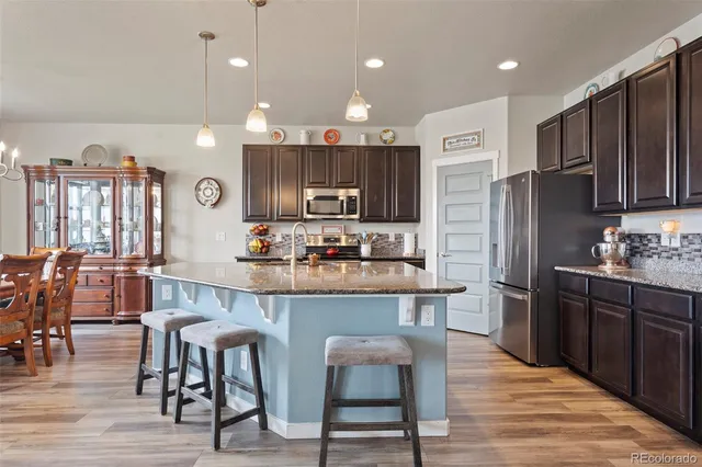 a kitchen with stainless steel appliances kitchen island granite countertop a refrigerator and a stove top oven