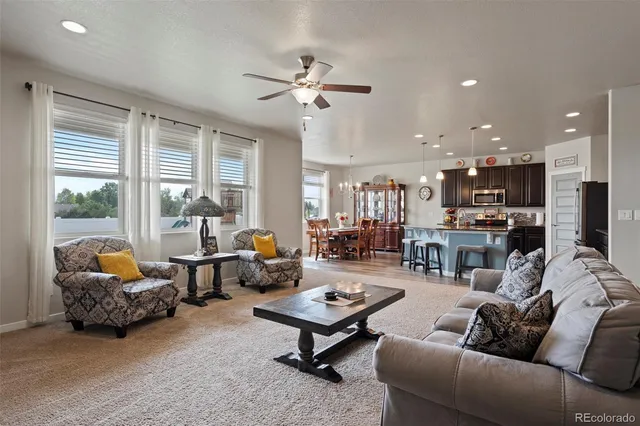 a living room with furniture kitchen view and a large window