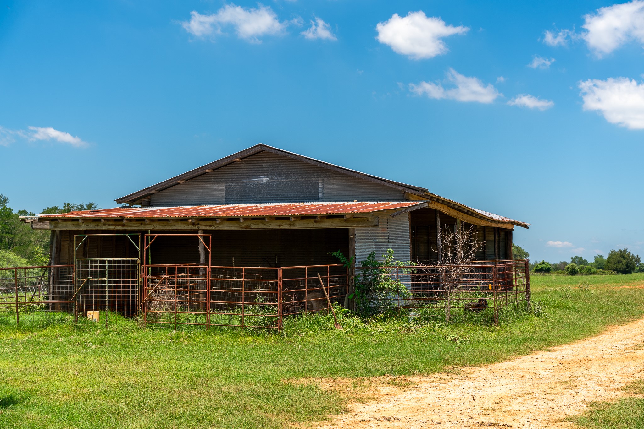 400 619th Spur Elgin, TX 78621 - Photo 36 of 40 A charming rustic barn with a weathered metal roof sits amidst a verdant field, ready for agricultural endeavors.