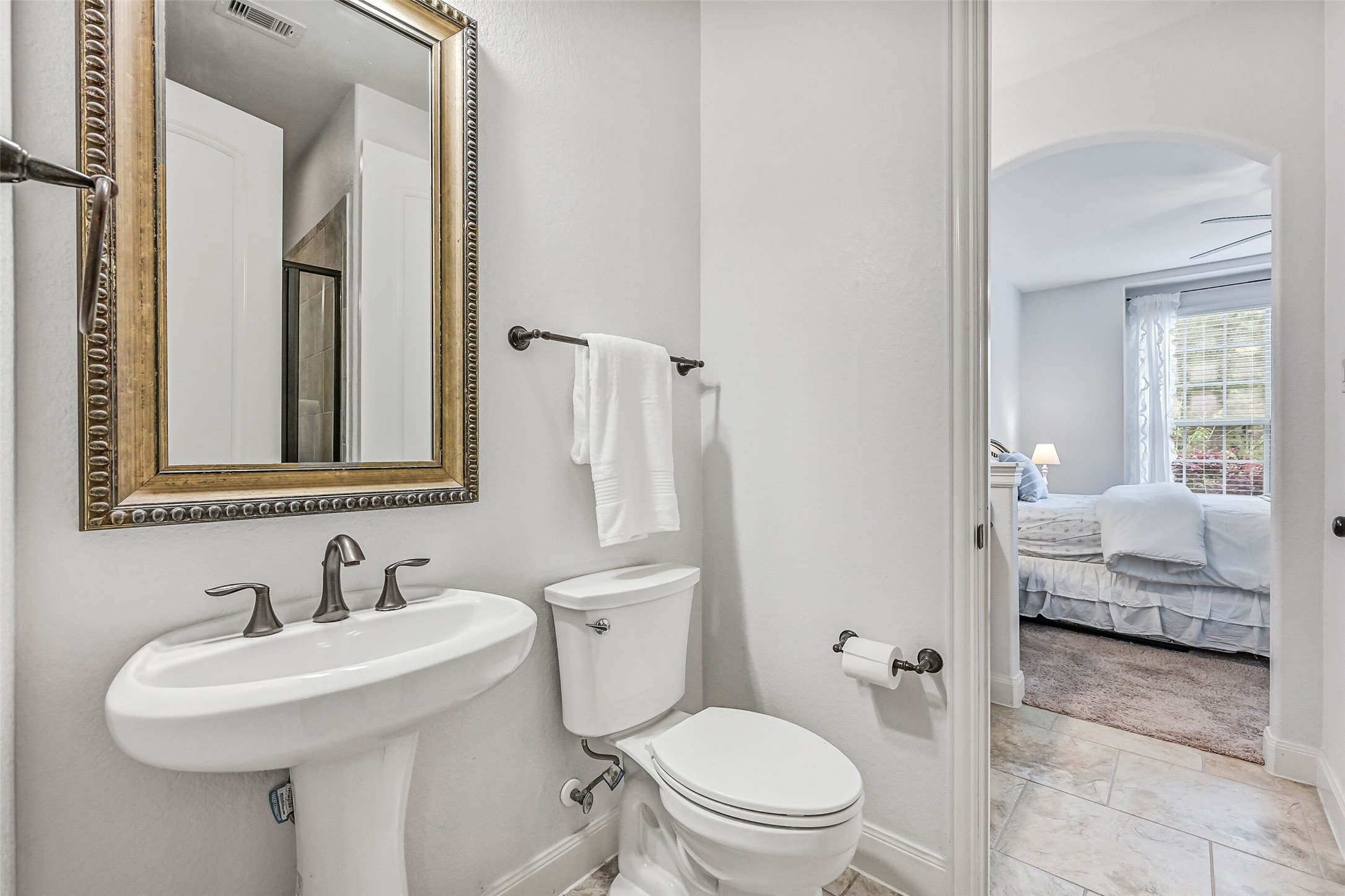 1008 Point Isabel Lane Friendswood, TX 77546 - Photo 26 of 50 Beyond the vanity, the bath continues into a shared Jack and Jill layout with a pedestal sink, a framed mirror, and an additional door to the hallway, allowing flexible use as a guest bath or secondary access point.