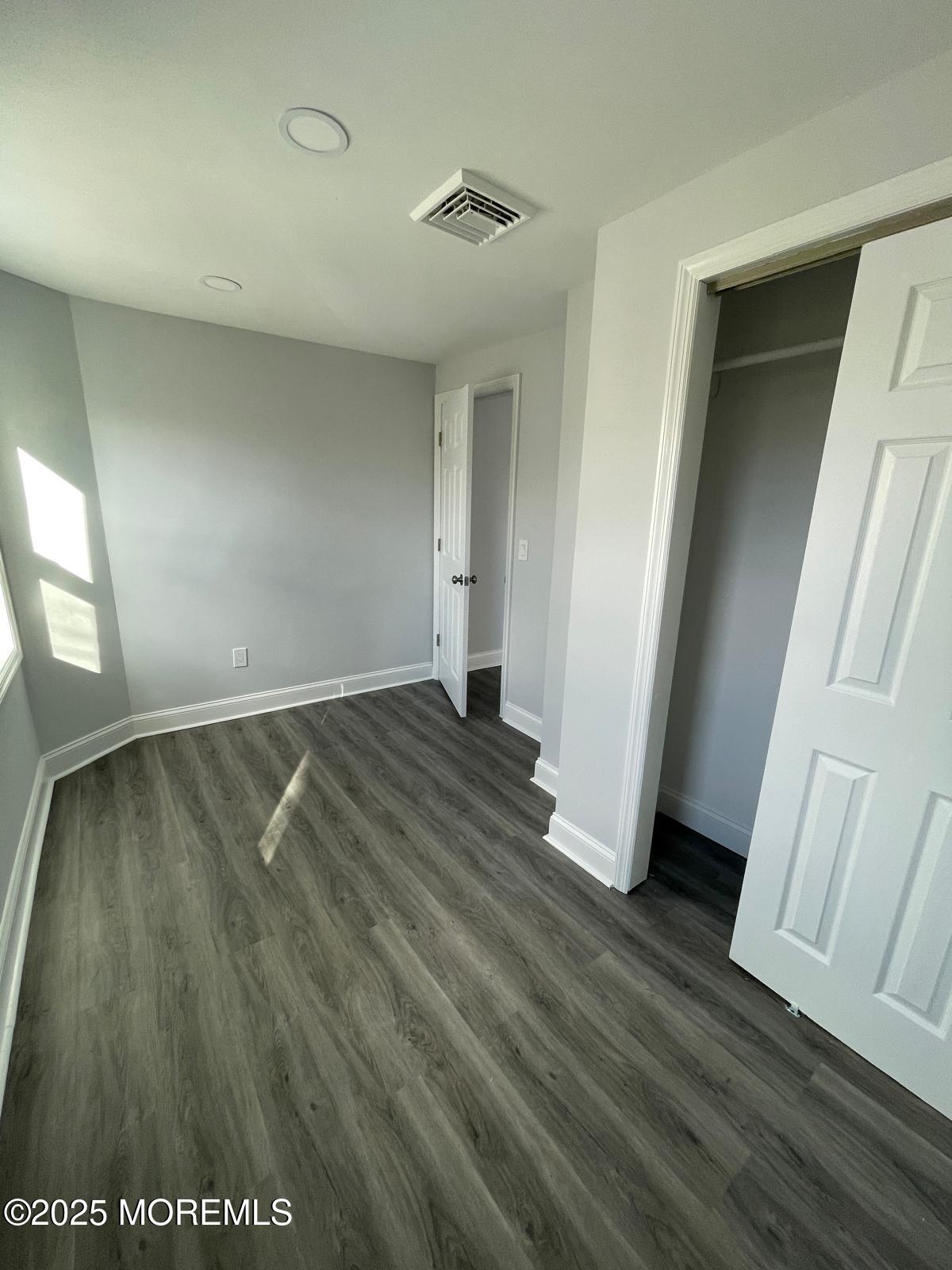 405 Myrtle Avenue Neptune Township, NJ 07753 - Photo 12 of 20 an empty room with wooden floor and windows