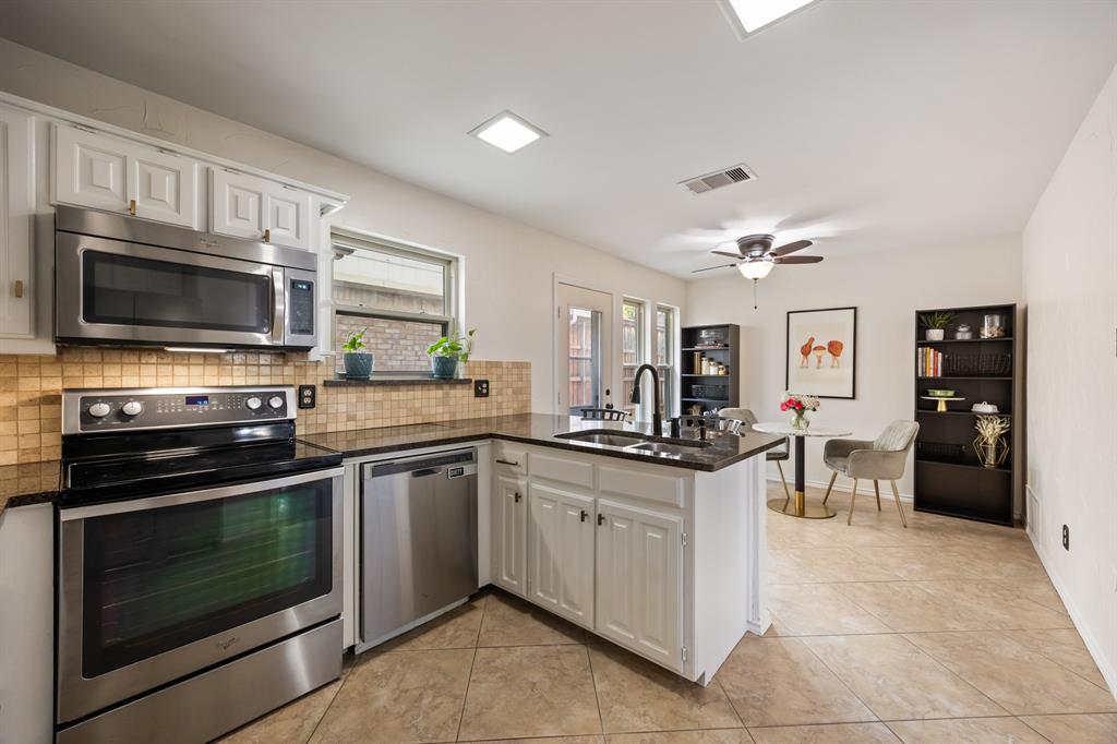 2807 Silverspring Road Carrollton, TX 75006 - Photo 15 of 37 Granite countertops and stainless steel appliances pair with peninsula seating and a bright breakfast nook for casual dining.