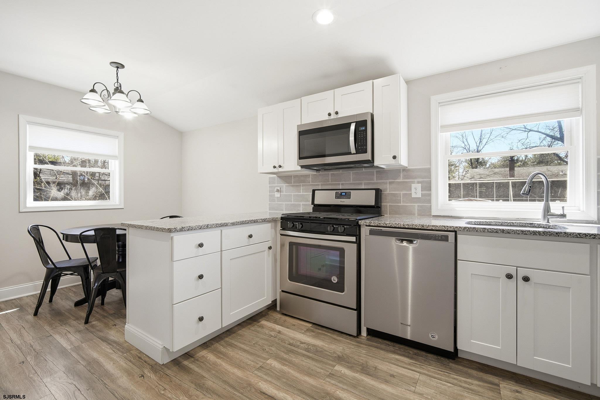 1103 Chelsea Road Absecon, NJ 08201 - Photo 11 of 34 a kitchen with stainless steel appliances granite countertop a stove top oven a sink dishwasher and a microwave oven with wooden floor