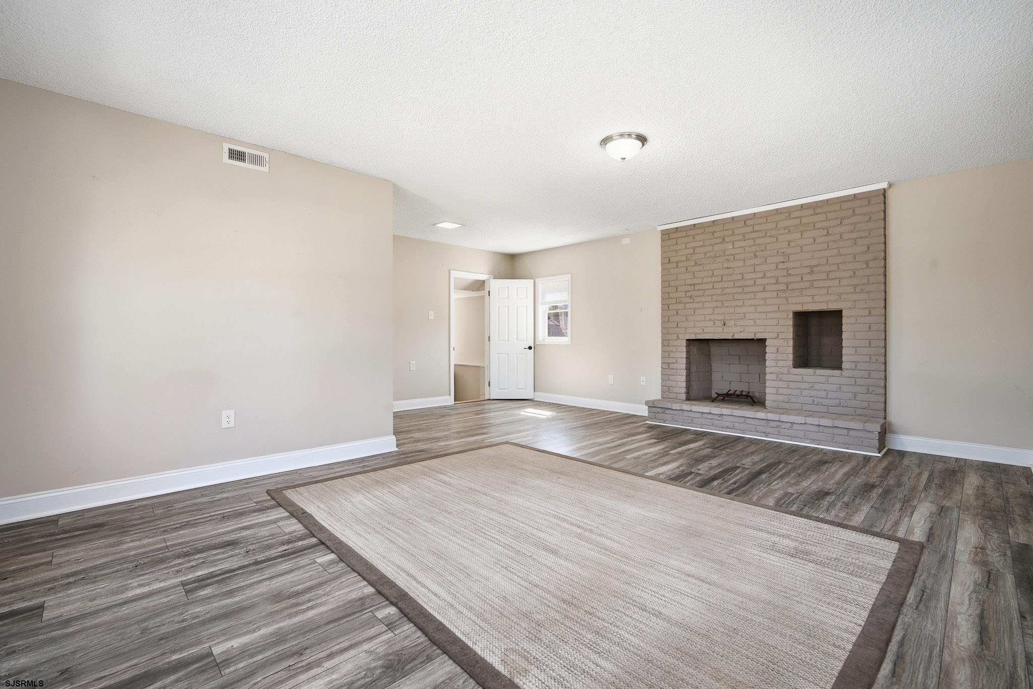 1103 Chelsea Road Absecon, NJ 08201 - Photo 18 of 34 a view of empty room with wooden floor and fireplace