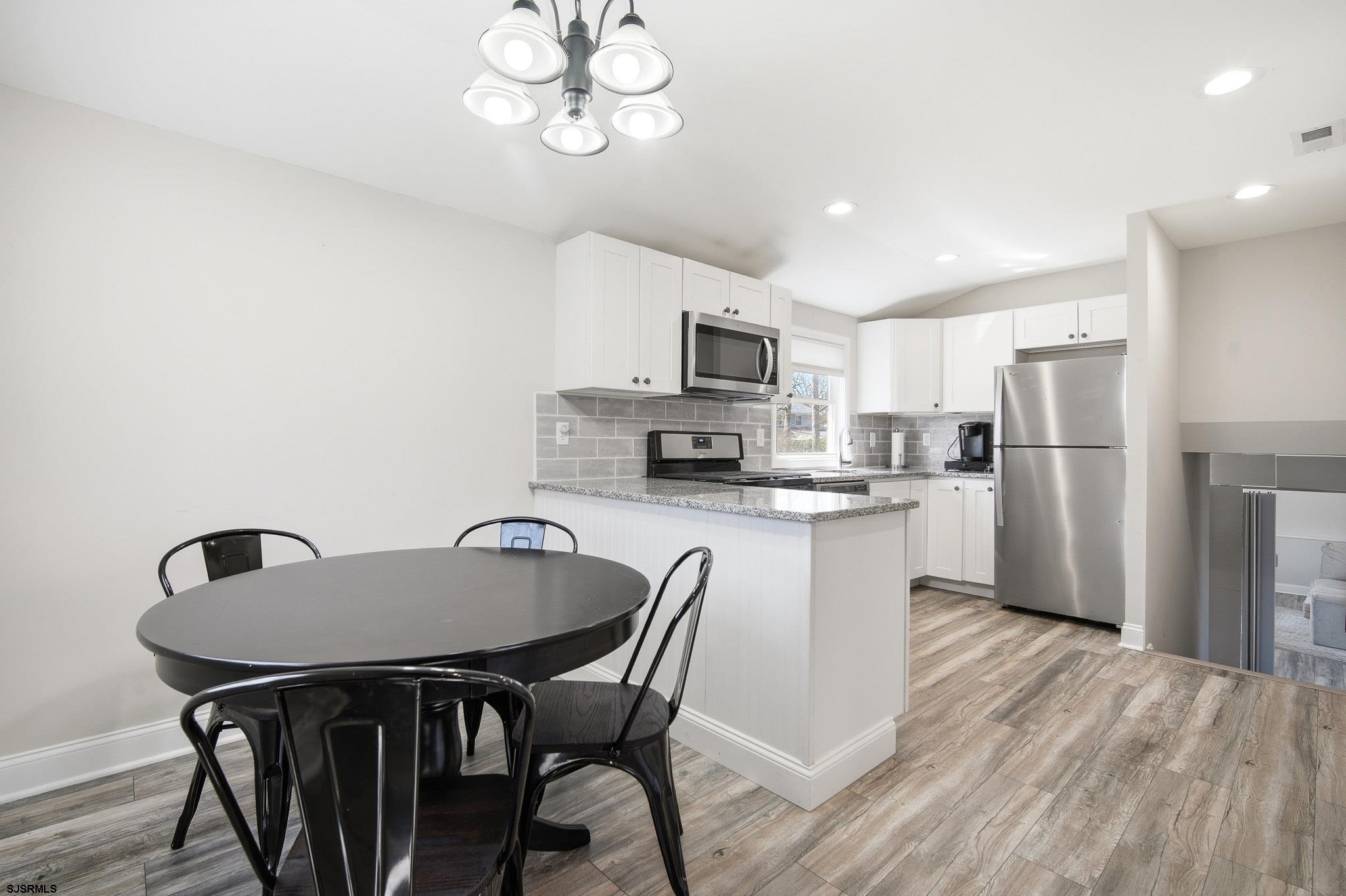 1103 Chelsea Road Absecon, NJ 08201 - Photo 10 of 34 a kitchen with stainless steel appliances granite countertop a dining table chairs refrigerator and microwave