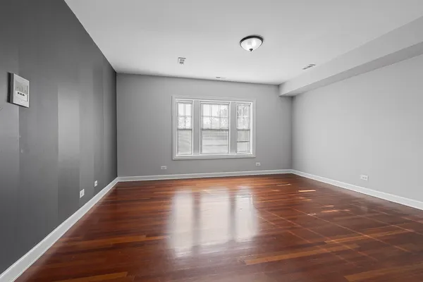 a view of an empty room with wooden floor and window