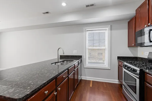 a kitchen with granite countertop a stove a sink and a microwave