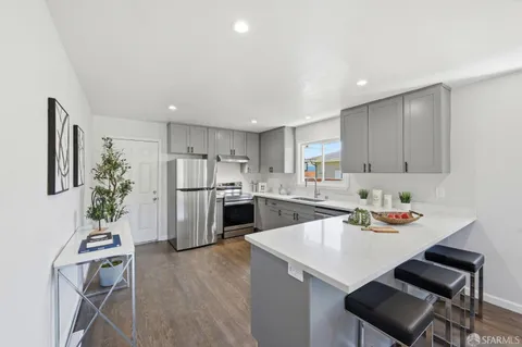 a large white kitchen with lots of white cabinets a sink and dishwasher with wooden floor