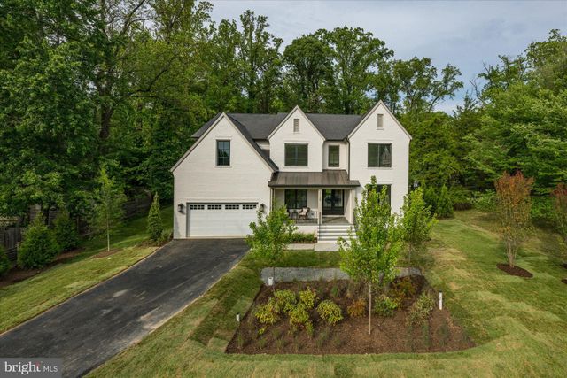 a view of a white house next to a yard with big trees
