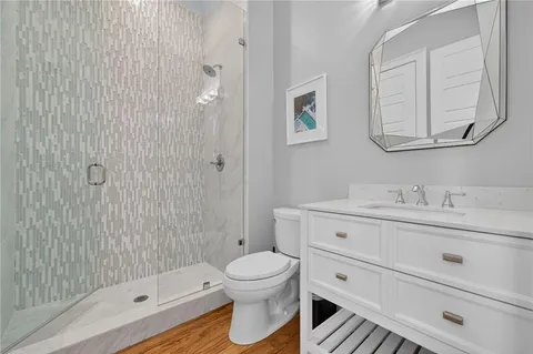 a bathroom with a toilet a sink a mirror and shower