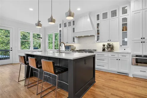 a kitchen with stainless steel appliances granite countertop a stove top oven a sink dishwasher a dining table and chairs with wooden floor