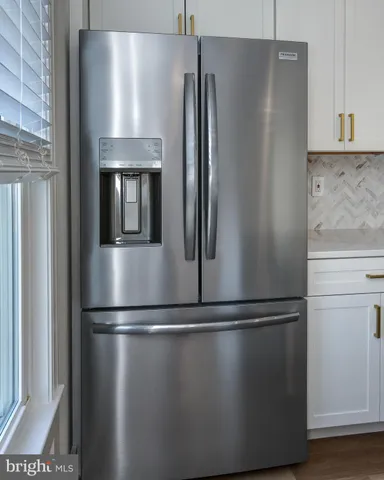 a close view of a refrigerator in kitchen and stainless steel appliances wooden cabinet