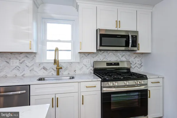 a kitchen with stainless steel appliances white cabinets granite counter tops and a window