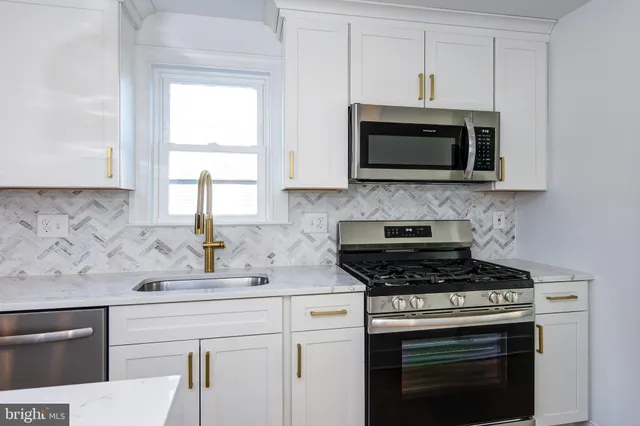 a kitchen with stainless steel appliances white cabinets granite counter tops and a window