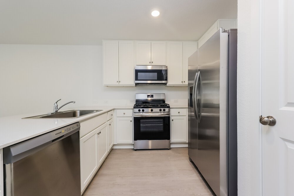 1527 Sunset Ridge Drive Conroe, TX 77306 - Photo 6 of 16 a kitchen with granite countertop a refrigerator stove and microwave