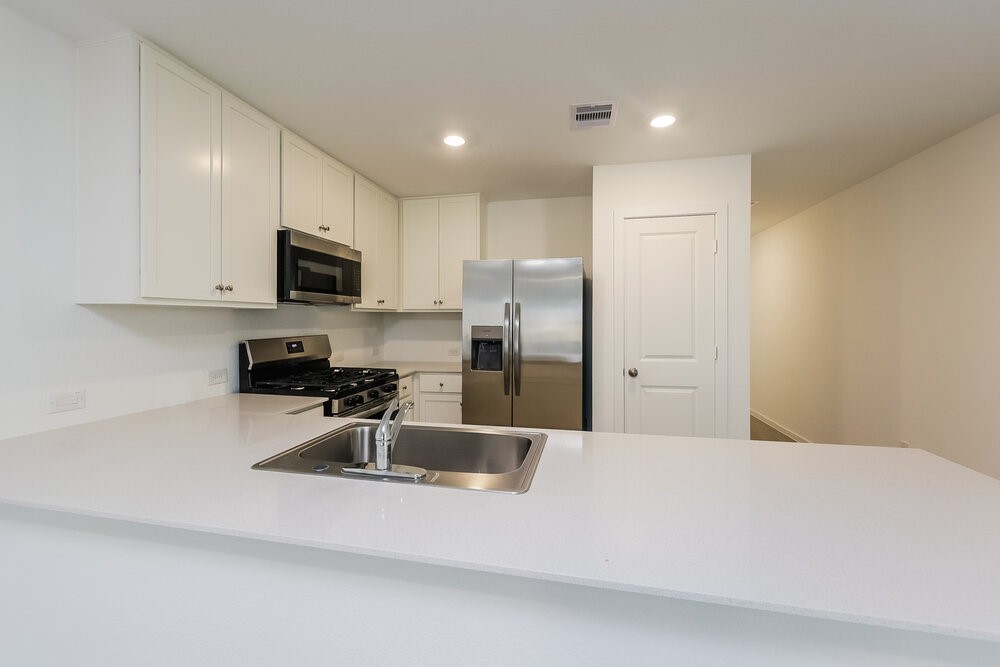 1527 Sunset Ridge Drive Conroe, TX 77306 - Photo 7 of 16 a kitchen with stainless steel appliances a refrigerator sink microwave and cabinets