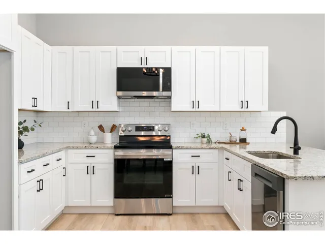a kitchen with stainless steel appliances granite countertop a stove a sink and white cabinets