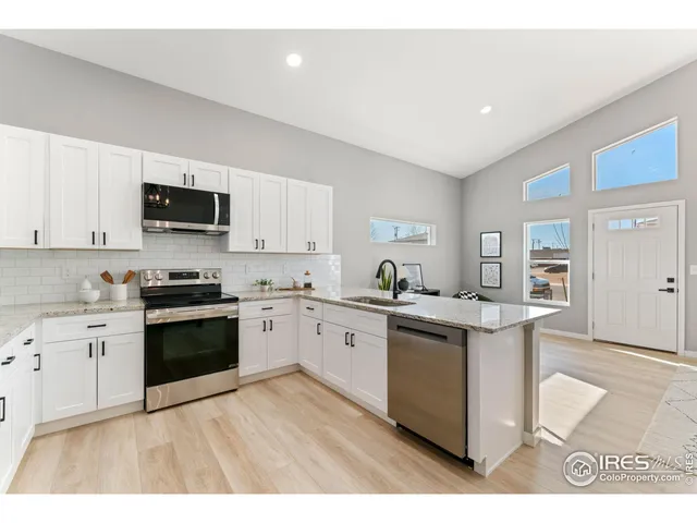 a kitchen with stainless steel appliances granite countertop a stove top oven a sink a microwave a counter space and cabinets