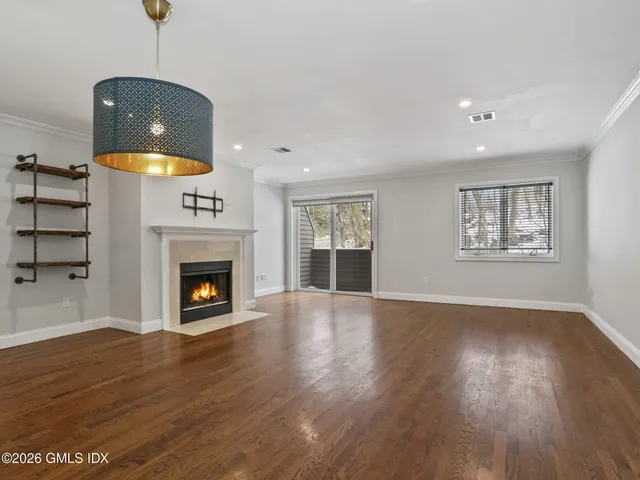 a view of an empty room with wooden floor fireplace and a window