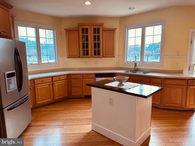 a kitchen with stainless steel appliances granite countertop a stove a sink dishwasher and a refrigerator with wooden floor