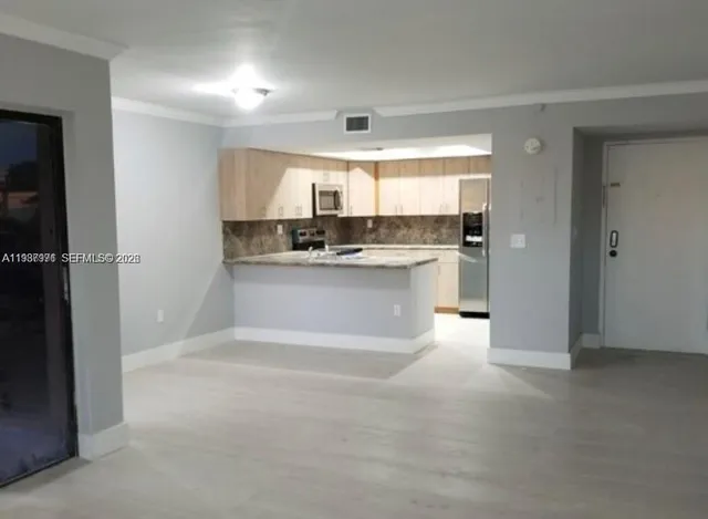 a view of a kitchen with a sink and dishwasher a refrigerator with white cabinets