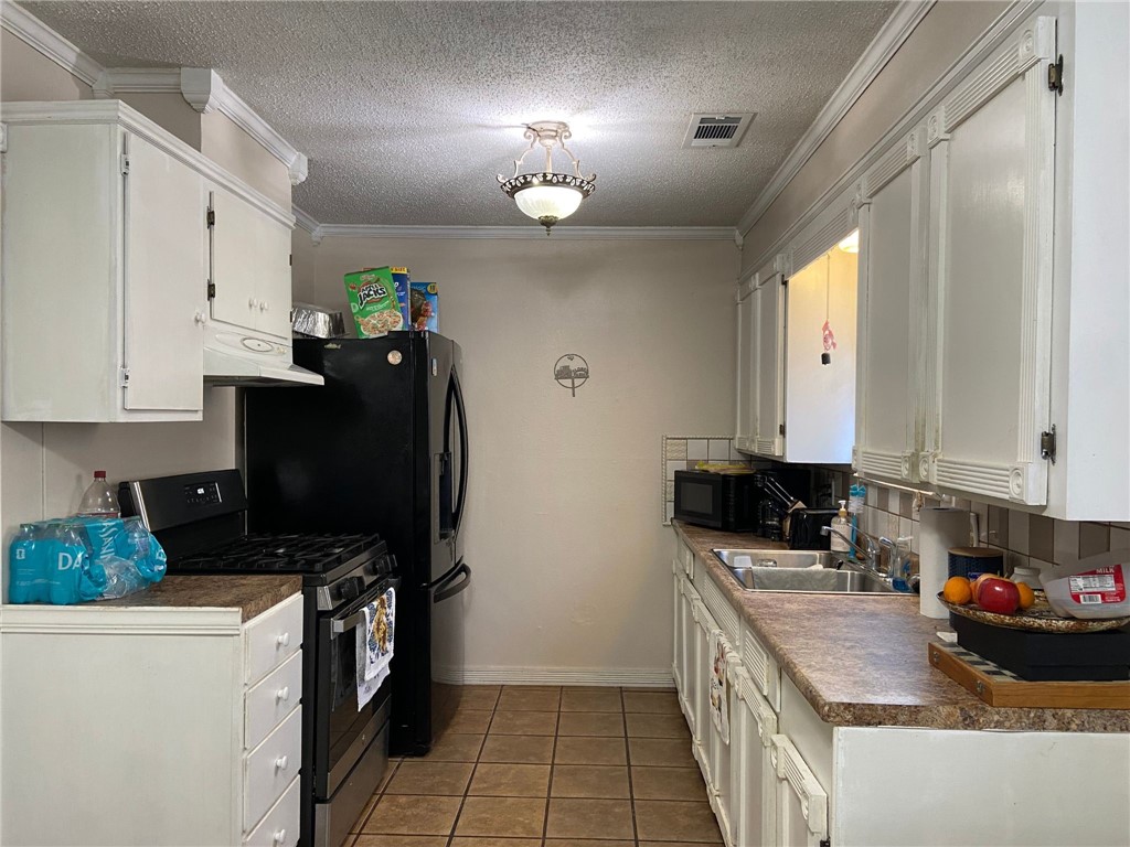 2102 Suarez Street Alice, TX 78332 - Photo 5 of 11 a kitchen with granite countertop a stove a sink a refrigerator and a microwave