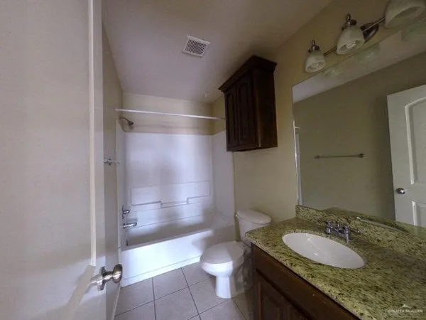 a bathroom with a granite countertop sink a toilet a mirror and shower