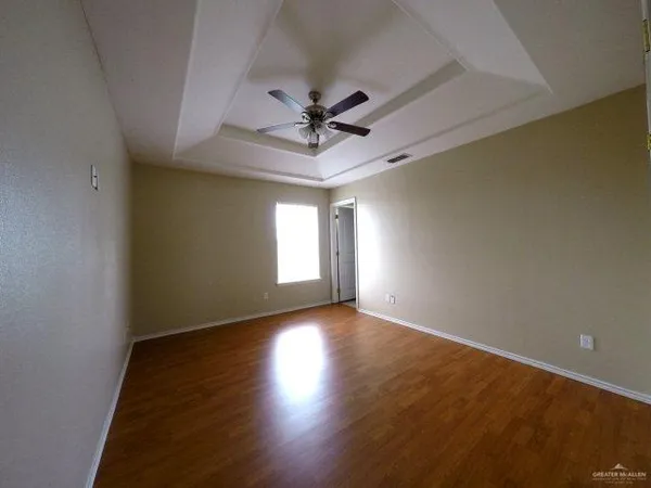 an empty room with wooden floor chandelier fan and windows