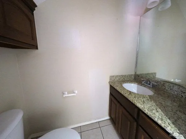 a bathroom with a granite countertop sink and a toilet
